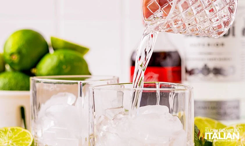 pouring white rum into glasses with ice