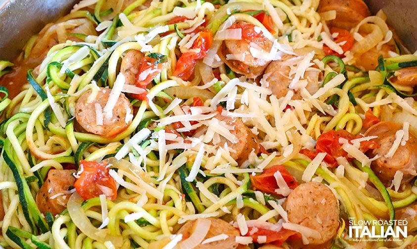 zoodles and sausage with tomatoes and onions topped with parmesan cheese