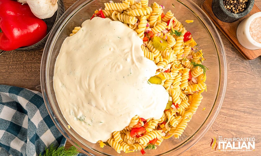adding dressing to dill pickle pasta salad