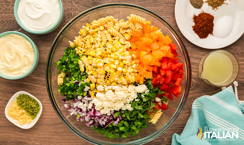 sliced veggies added to large bowl of pasta