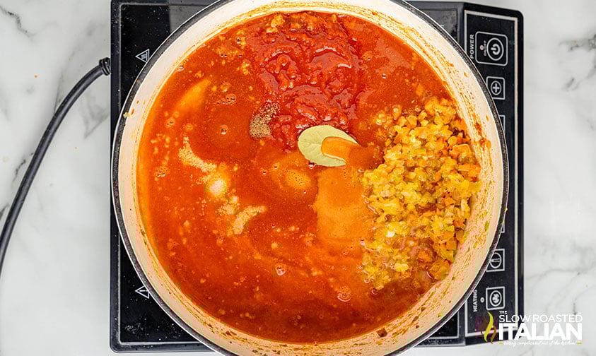 adding chicken stock crushed tomatoes and spices to dutch oven