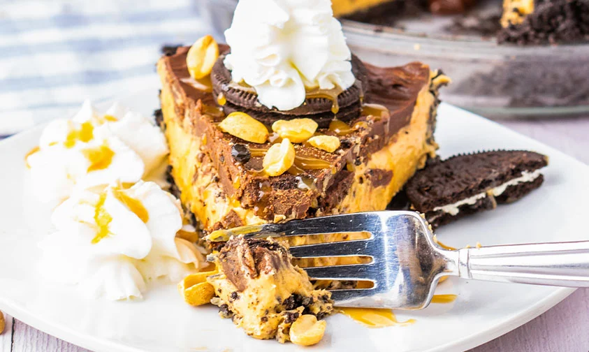 closeup: fork slicing into a piece of chocolate peanut butter pie with oreos
