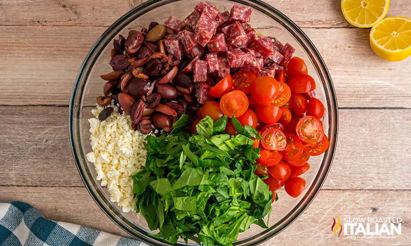 adding chopped veggies and salami to cooked orzo in large mixing bowl