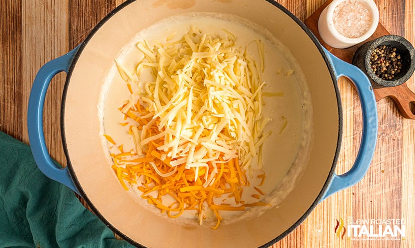 adding shredded cheese to roux in large pot