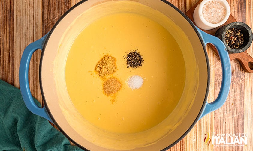adding seasoning to melted cheese sauce