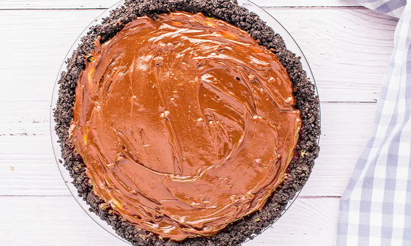 overhead: chocolate mixture poured over oreo chocolate peanut butter pie