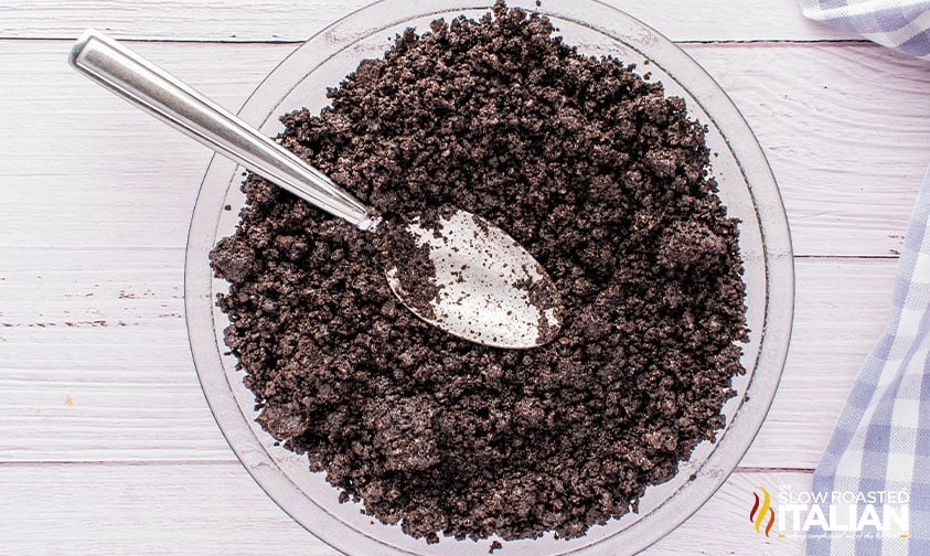 overhead: crushed peanut butter pie oreos in a mixing bowl with a spoon