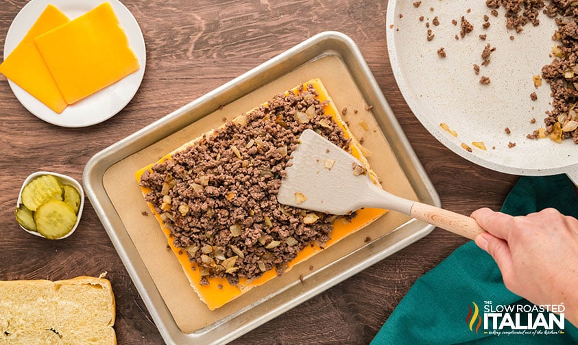 adding sliced cheese and ground beef mixture to sheet pan sliders