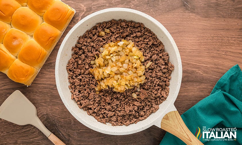 adding caramelized onions to cooked ground beef