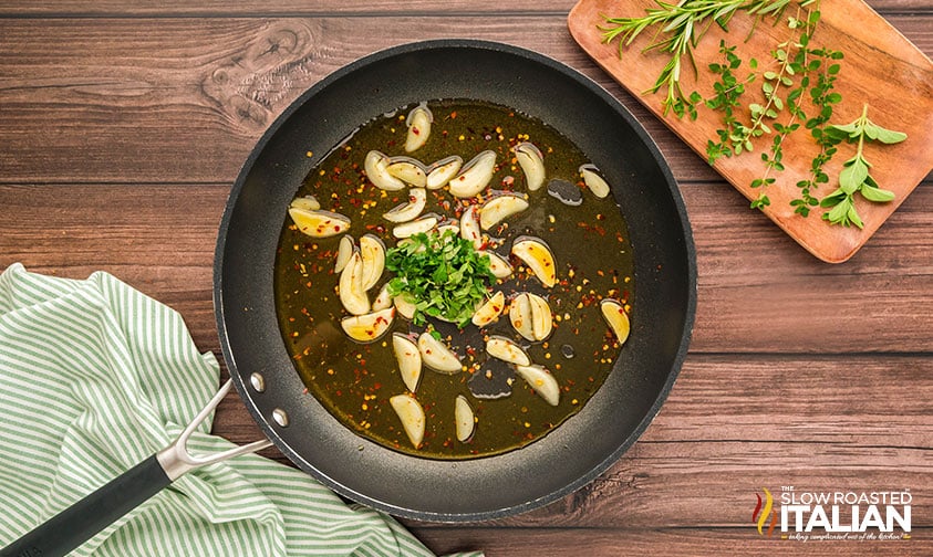 adding oil and herbs to cooked shrimp in skillet for midnight spaghetti recipe