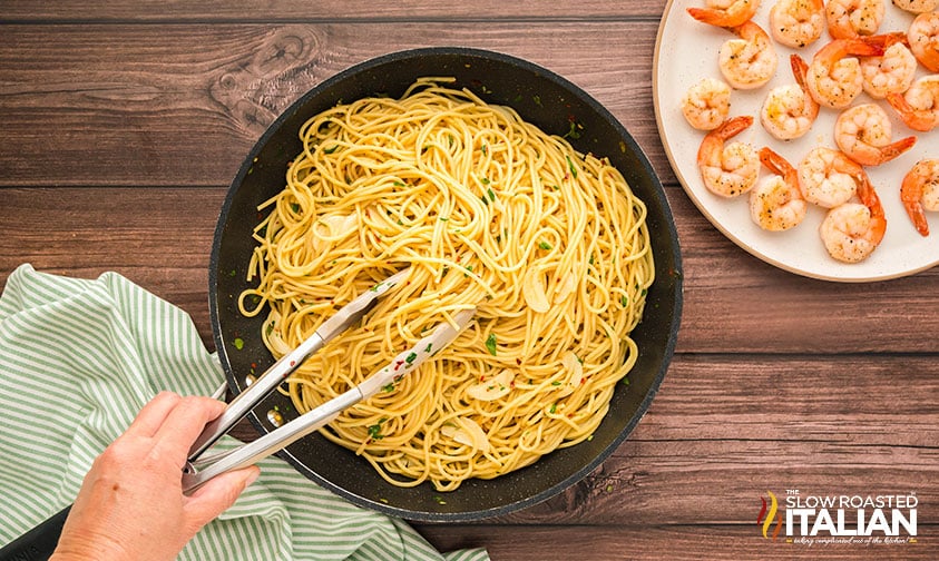 tossing spaghetti with herb infused oil