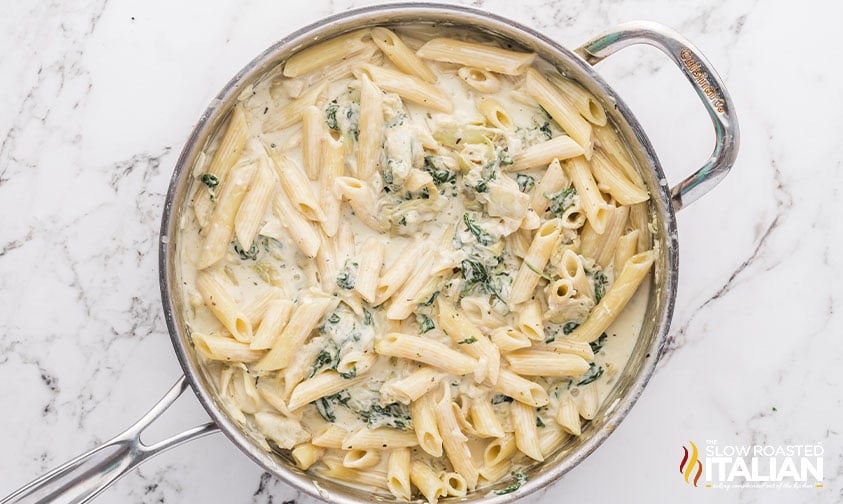 pasta added to skillet with spinach, artichokes and onion