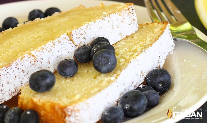 slices of moist lemon pound cake on plate with fresh blueberries