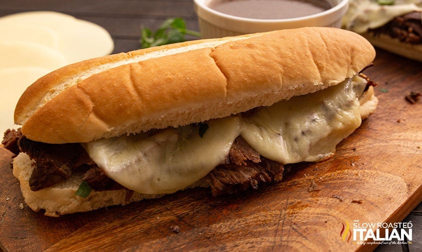 french dip sandwich with melted cheese on cutting board