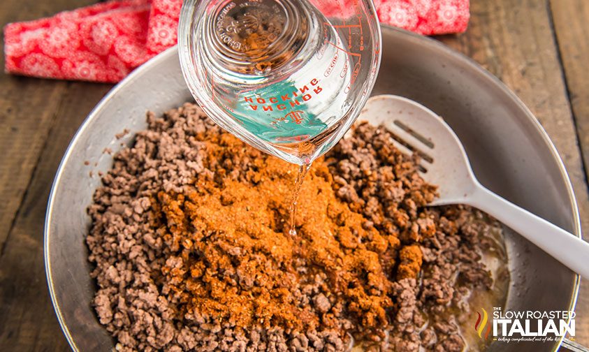 pouring water into skillet with ground beef and taco seasoning