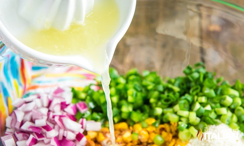pouring lime juice over street corn salad ingredients