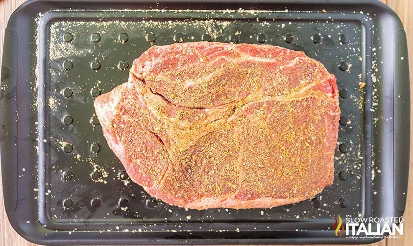 chuck roast on grill tray coated in dry rub