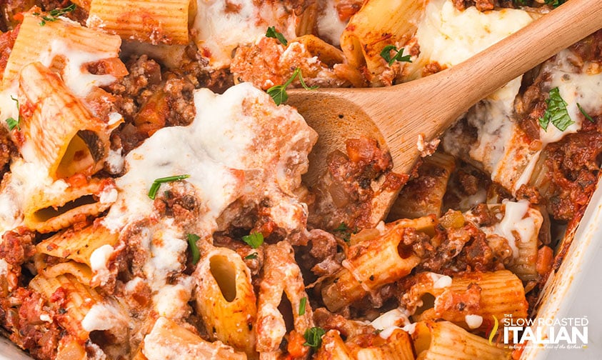 serving baked pasta bolognese with a wooden spoon