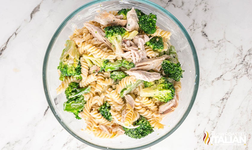 cooked chicken, steamed broccoli and cooked pasta in a large mixing bowl