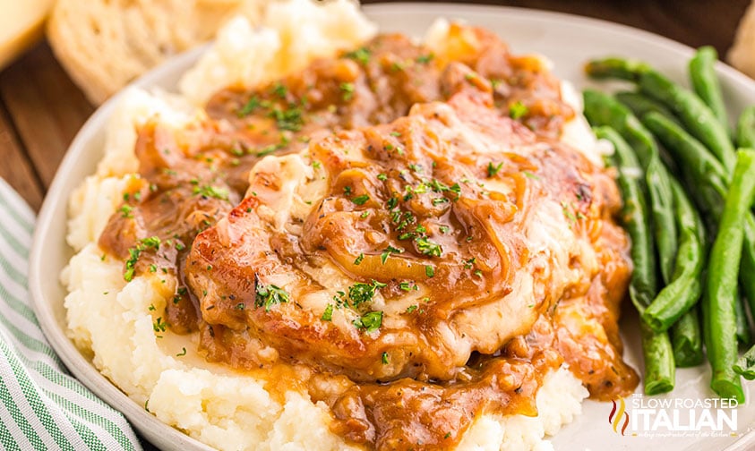 french onion pork chops on a pile of mashed potatoes