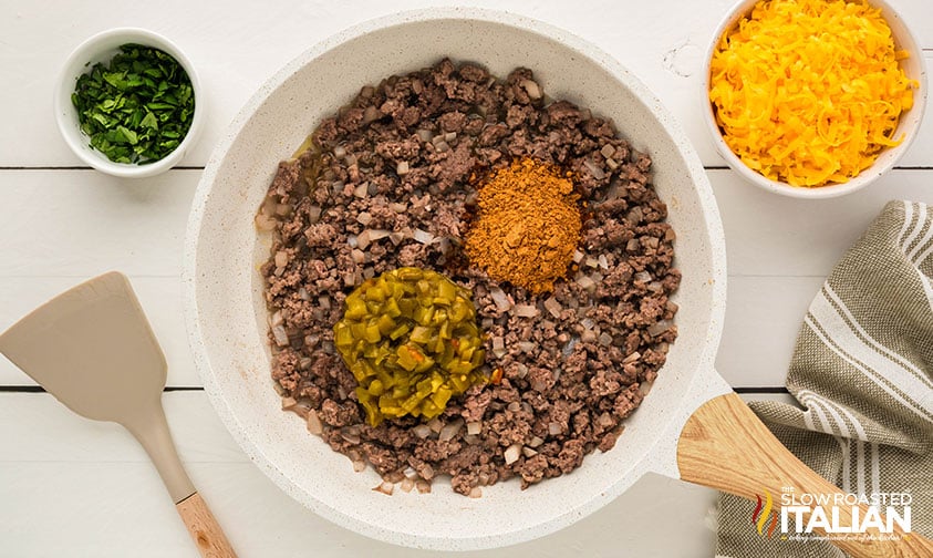 adding seasoning and diced green chilies browned ground beef