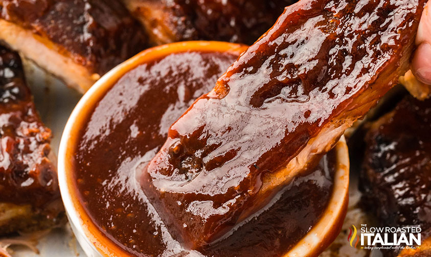 closeup of sheet pan ribs dipped in barbecue sauce
