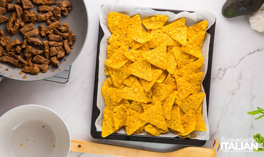 tortilla chips on a parchment lined baking sheet