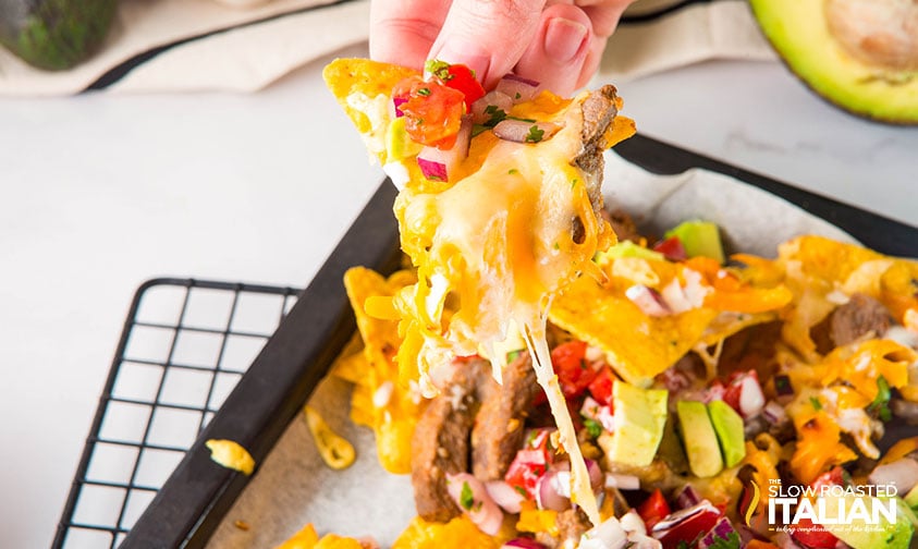 hand grabbing a sheet pan steak nacho