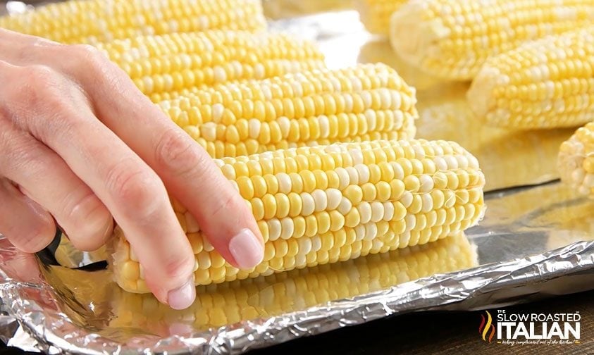 placing corn on the cob on a foil-lined baking sheet