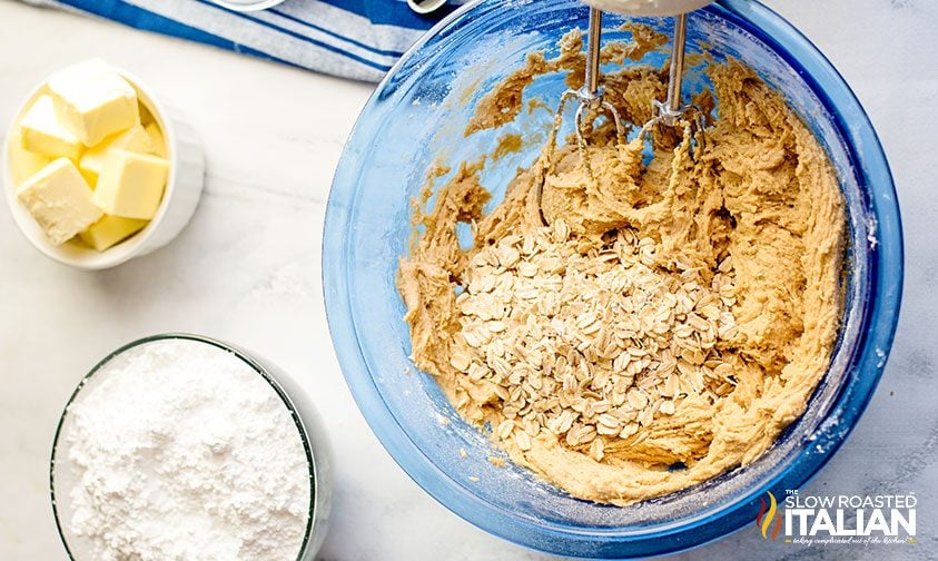 electric mixer in bowl of peanut butter cookie dough with oats
