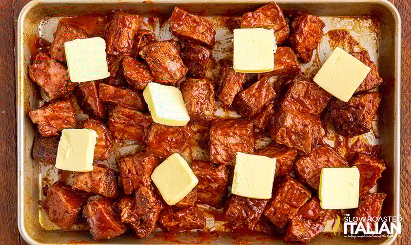 cubes of cooked chuck roast on sheet pan topped with pats of butter
