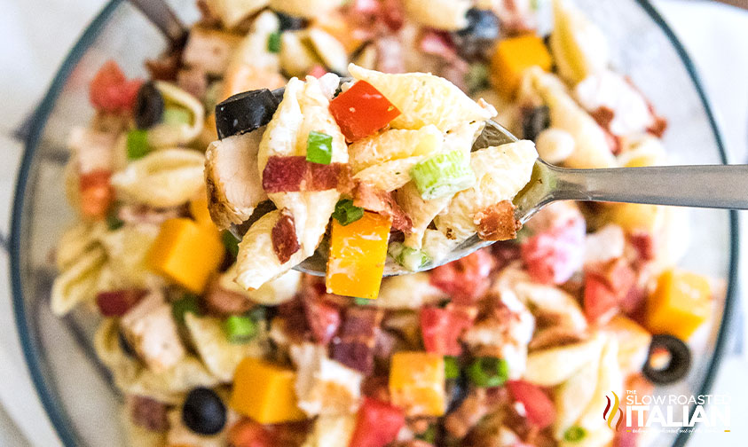 spoonful of chicken bacon ranch pasta salad held over bowl