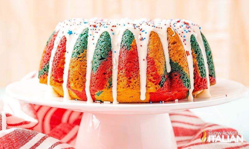 glazed red white and blue cake with sprinkles on a white cake stand