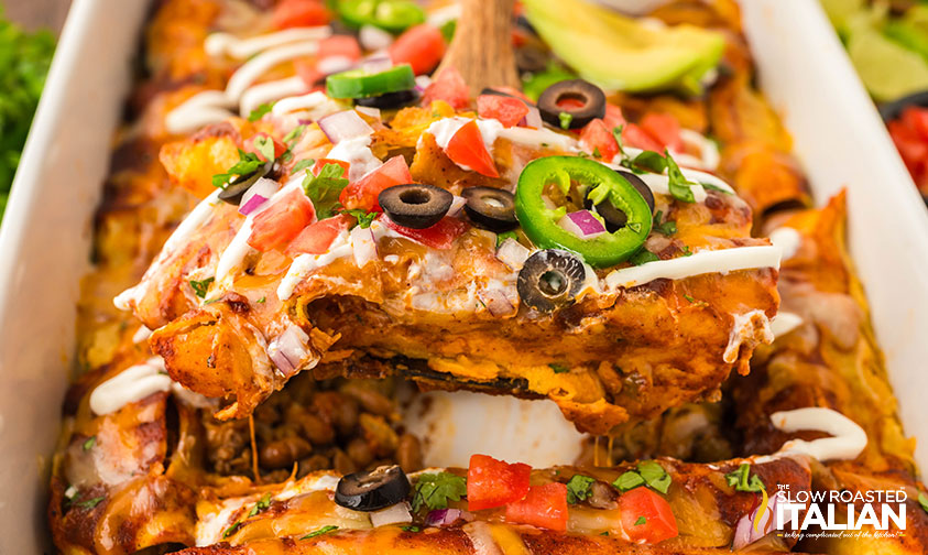 serving beef and bean enchiladas from a baking dish