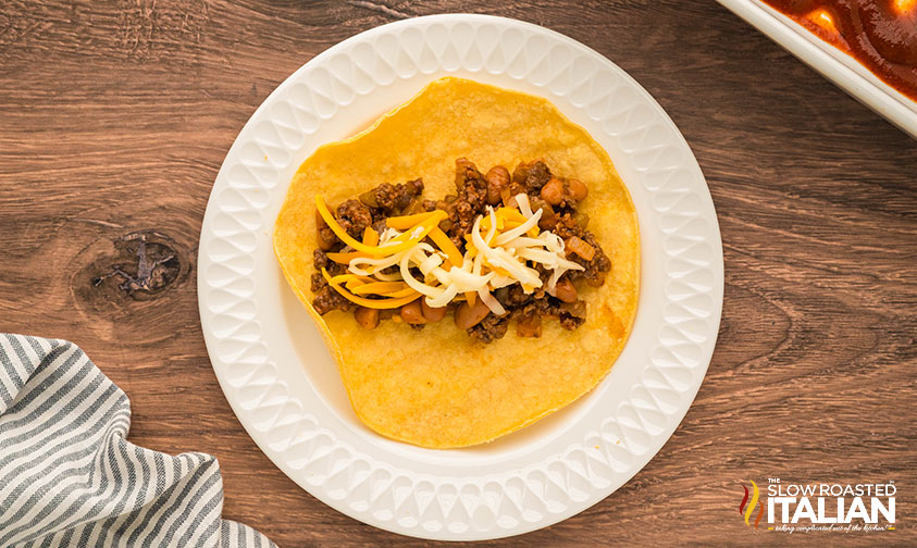adding enhcilada mixture and shredded cheese to tortilla