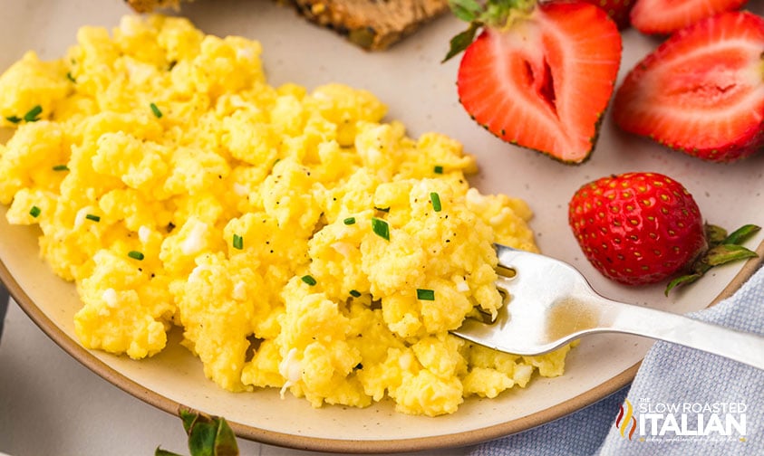 creamy cottage cheese eggs on a plate with sliced strawberries
