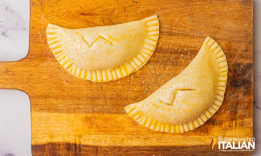 folded pie dough with pumpkin filling crimped with a lightning bolt scored in the center