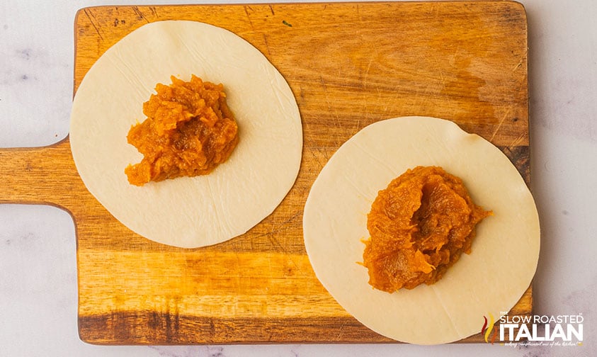 rolled and cut dough and a cutting board with creamy pumpkin filling in the middle