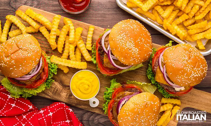 four stovetop burger on a wood board with crinkle cut fries