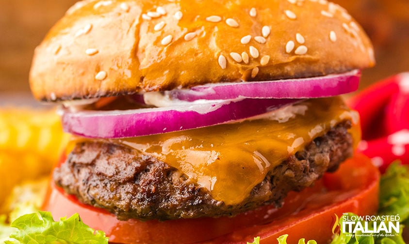 closeup of stovetop burgers with lettuce, onion, tomato and cheese