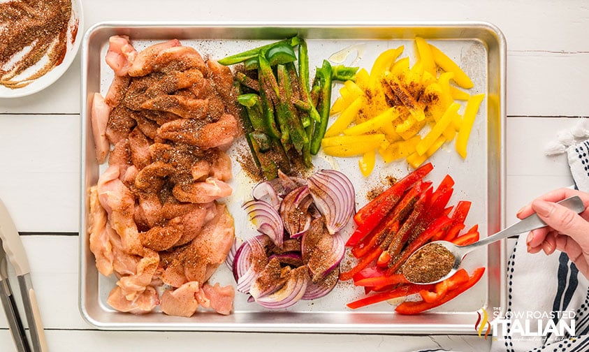 adding seasoning to sheet pan chicken fajitas ingredients