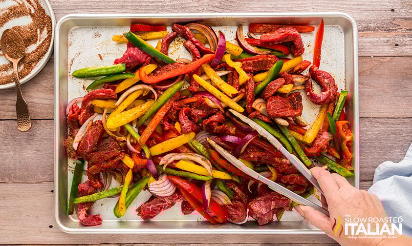 tossing steak fajita sheet pan ingredients
