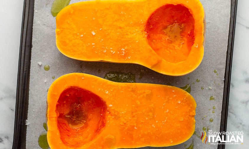 preparing butternut squash for the oven on a baking sheet