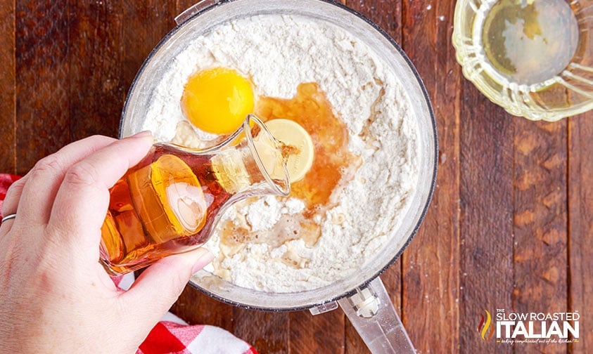 pouring marsala wine into food processor with flour and egg for cannoli shell recipe