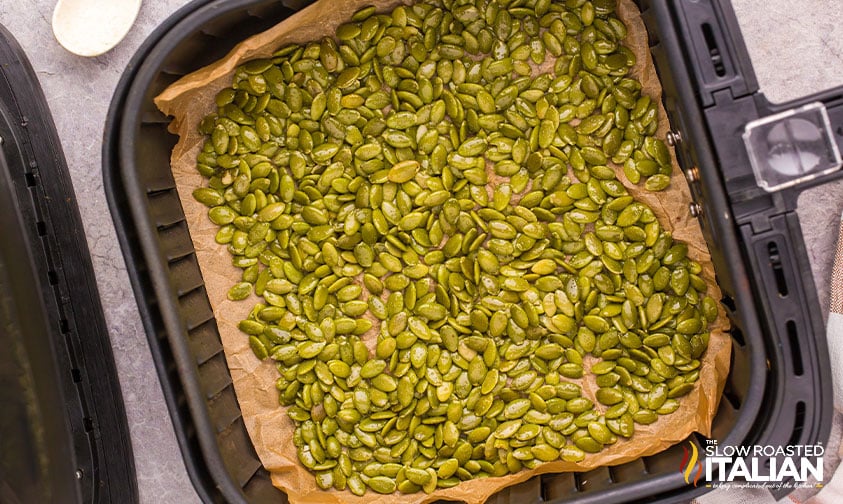 raw pumpkin seeds on parchment paper in air fryer basket