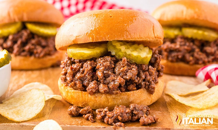 easy sloppy joes on a bun with sliced pickles sitting on a cutting board