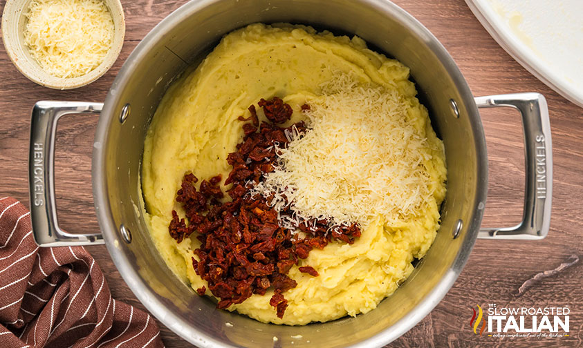 adding sun-dried tomatoes and parmesan cheese to baked mashed potatoes recipe