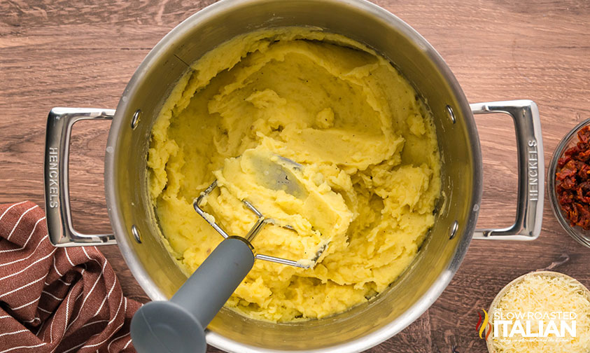 mashing potatoes in a large pot