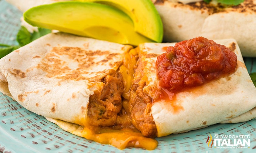 closeup of a sliced bean and cheese burrito on a plate