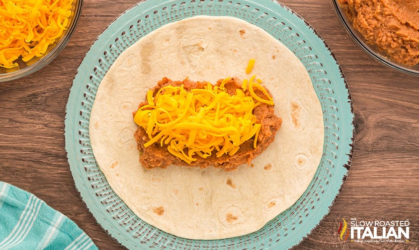 adding bean and cheese burrito filling to tortilla